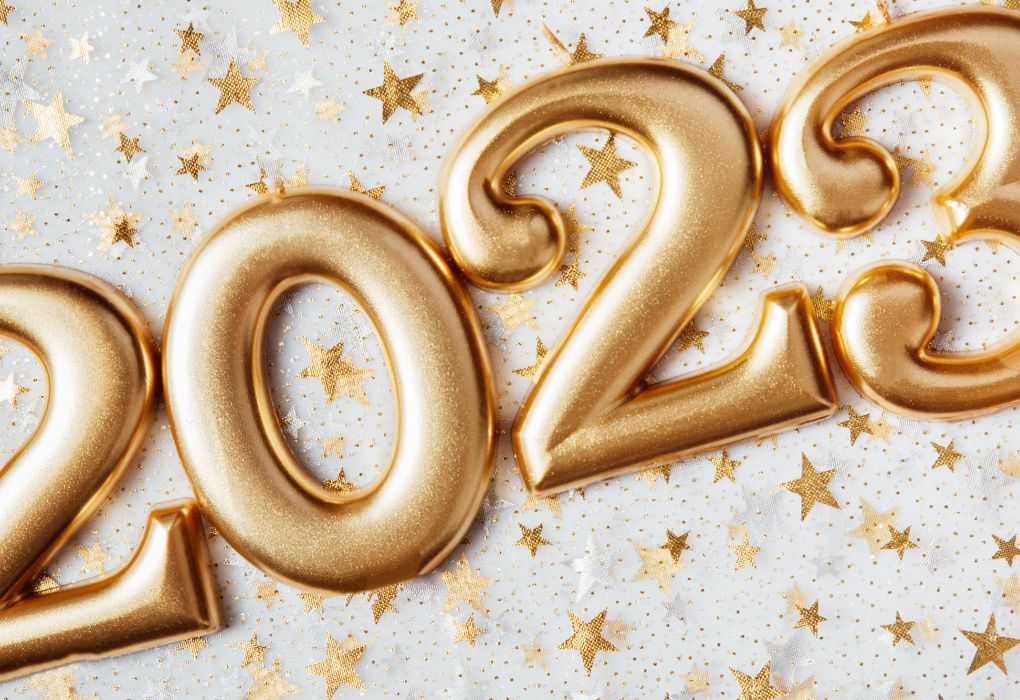 Goldene Luftballons in Form der Zahl 2023 auf hellem Hintergrund mit Sternkonfetti