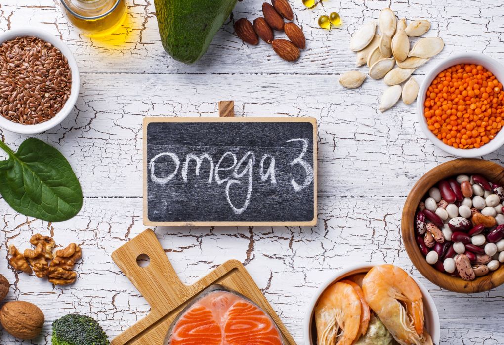 Verschiedene Lebensmittel wie Nüsse, Lachs, Samen und Öle um eine Tafel mit Schriftzug „Omega 3“