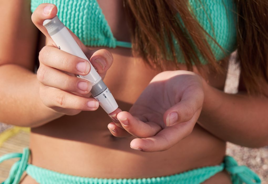 Frau in Bikini macht Diabetes Selbsttest