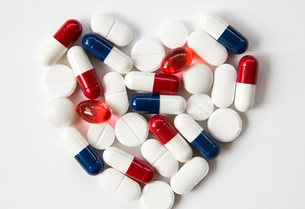 Rote, blaue und weiße Kapseln zu einem Herz auf weißem Hintergrund geformt