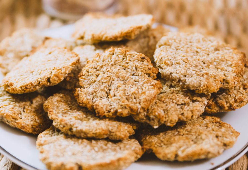 Teller mit goldbraunen Cookies aus Hafer und Körnern, angerichtet auf weißem Tell