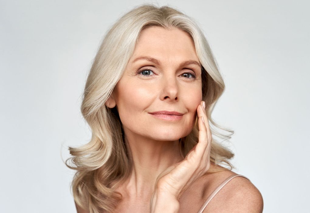 Reife Frau mit heller Haut lächelt, Symbol für Hautgesundheit.