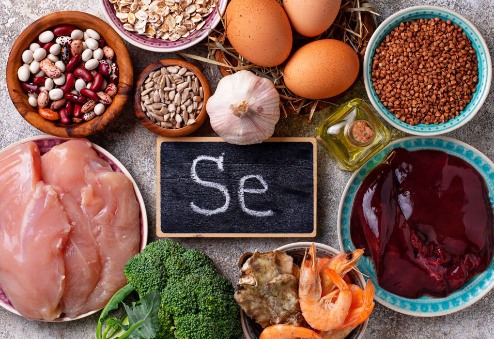 Auswahl an selenreichen Lebensmitteln wie Nüsse, Fisch, Fleisch, Eier und Gemüse mit Kreidetafel „Se“