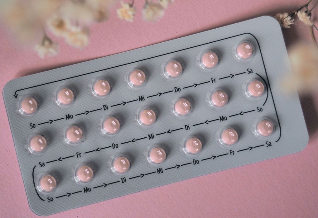 Silberne Blisterpackung mit rosa Tabletten vor rosa Hintergrund