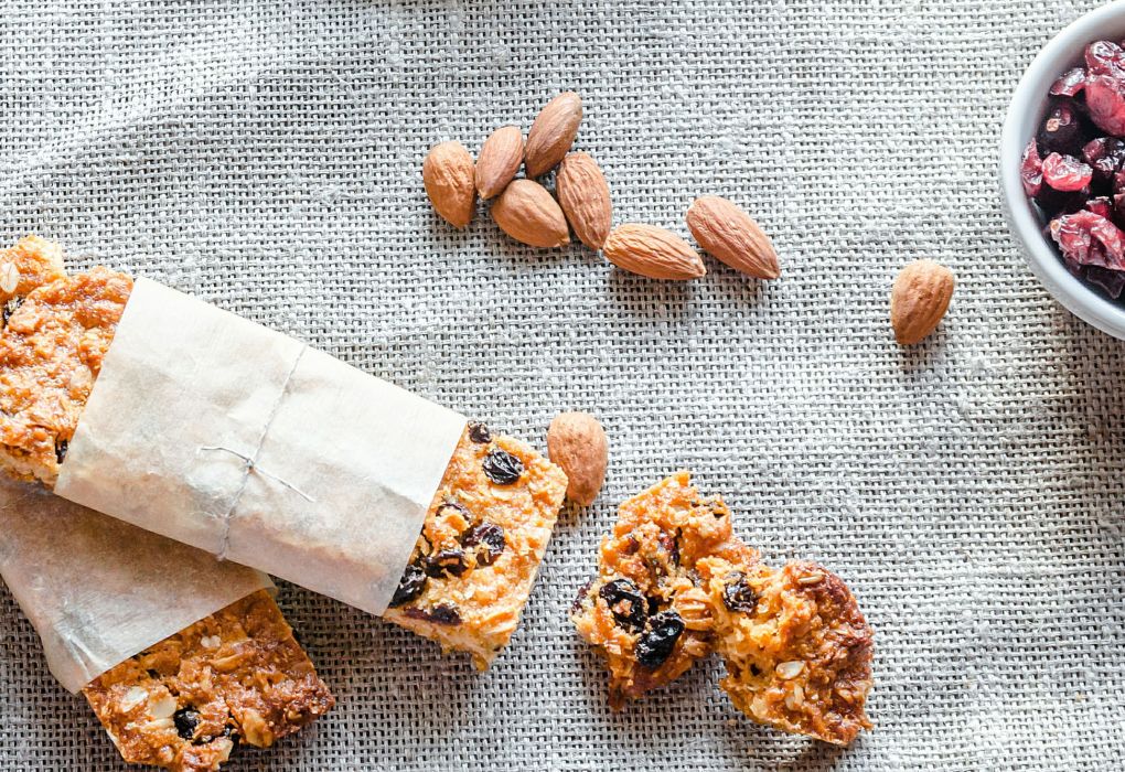 Verschiedene Müsliriegel mit Nüssen und Haferflocken auf grauer Unterlage