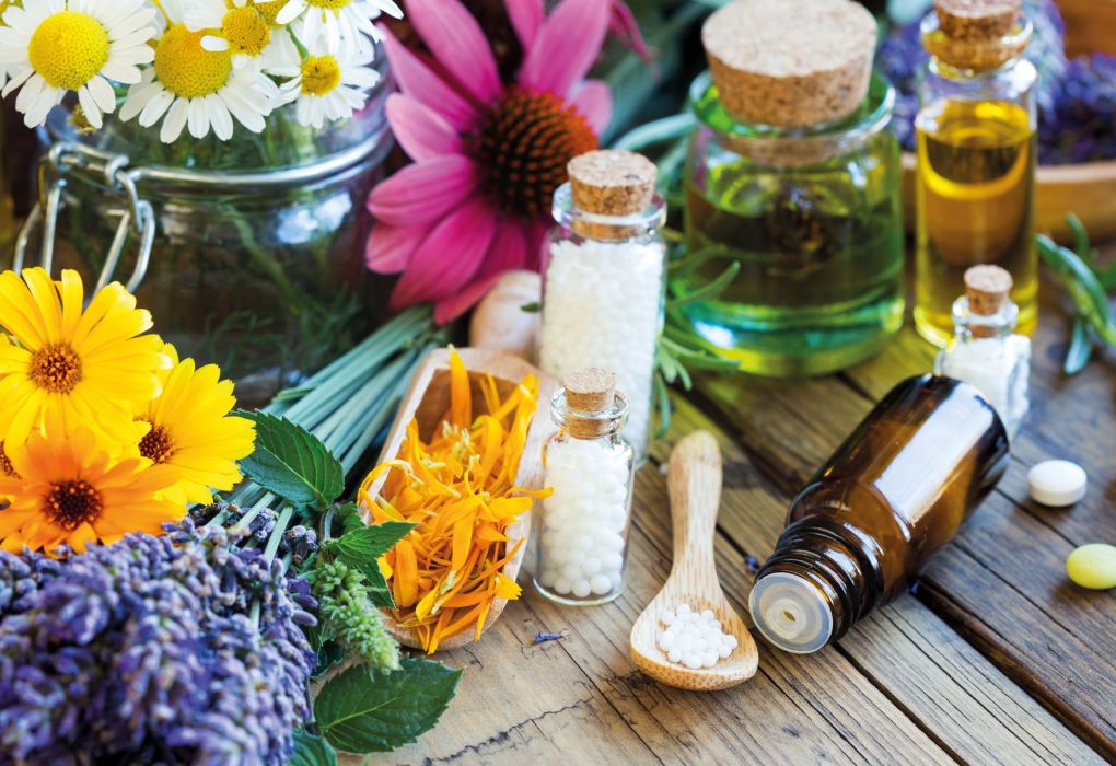 Fläschchen mit Globuli und Heilpflanzen als Symbolbild für Homöopathie