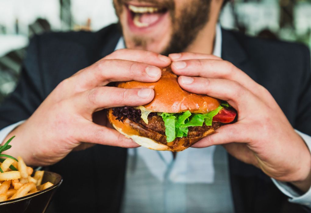 Man isst Burger, im Bild sind Pommes sichtbar