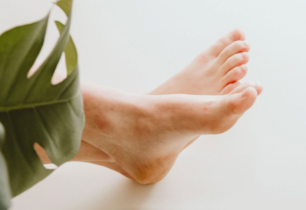 Zwei gestreckte Füsse in Nahaufnahme mit einem grünen Blatt