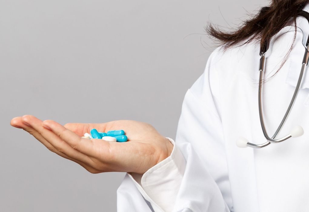 Frau hält bunte Tabletten und Kapseln in der Hand
