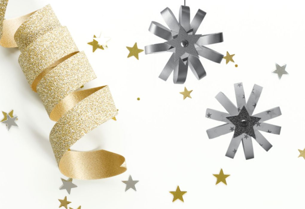 Goldene Geschenkbänder und silberne Papiersterne auf weißem Untergrund