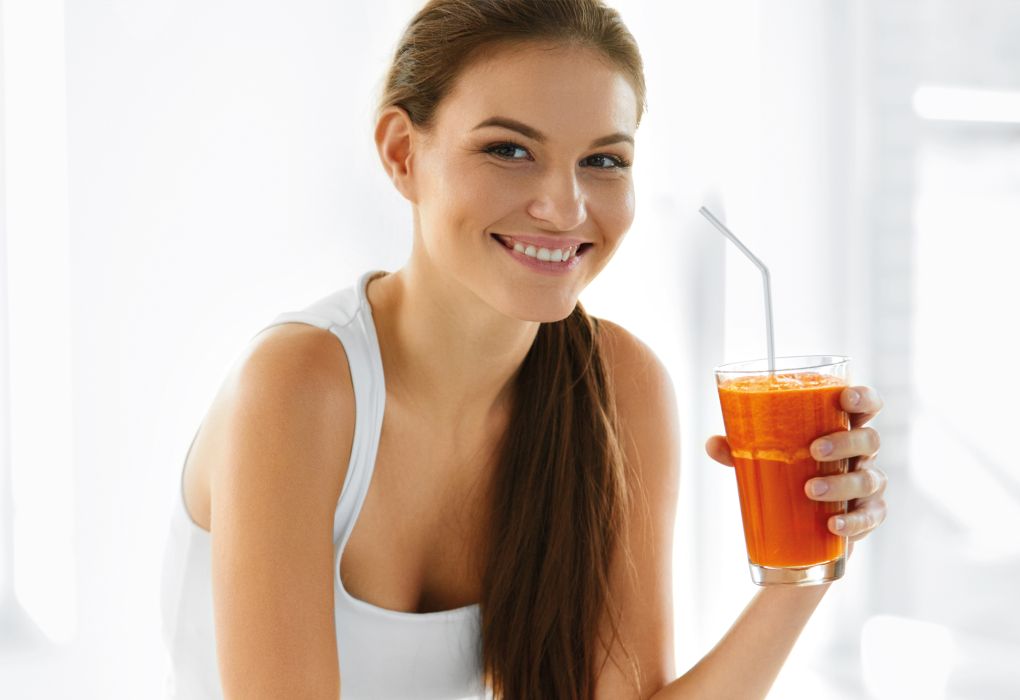 Junge Frau trinkt frisch gepressten Saft während einer Fastenkur