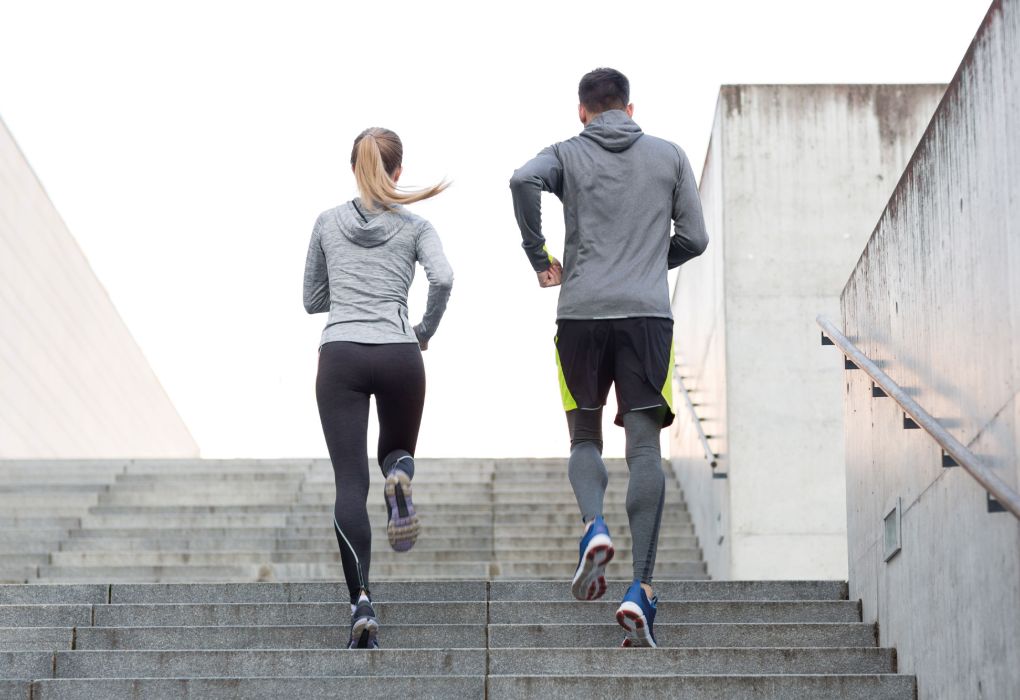 Zwei Personen in Sportkleidung laufen eine Treppe hoch als Trainingseinheit