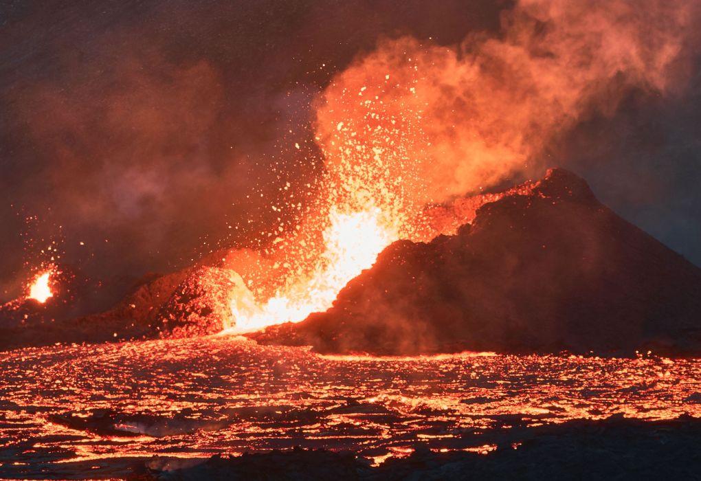 Aktiver Vulkan stößt Feuer, Rauch und Lava aus in der Nachtlandschaft