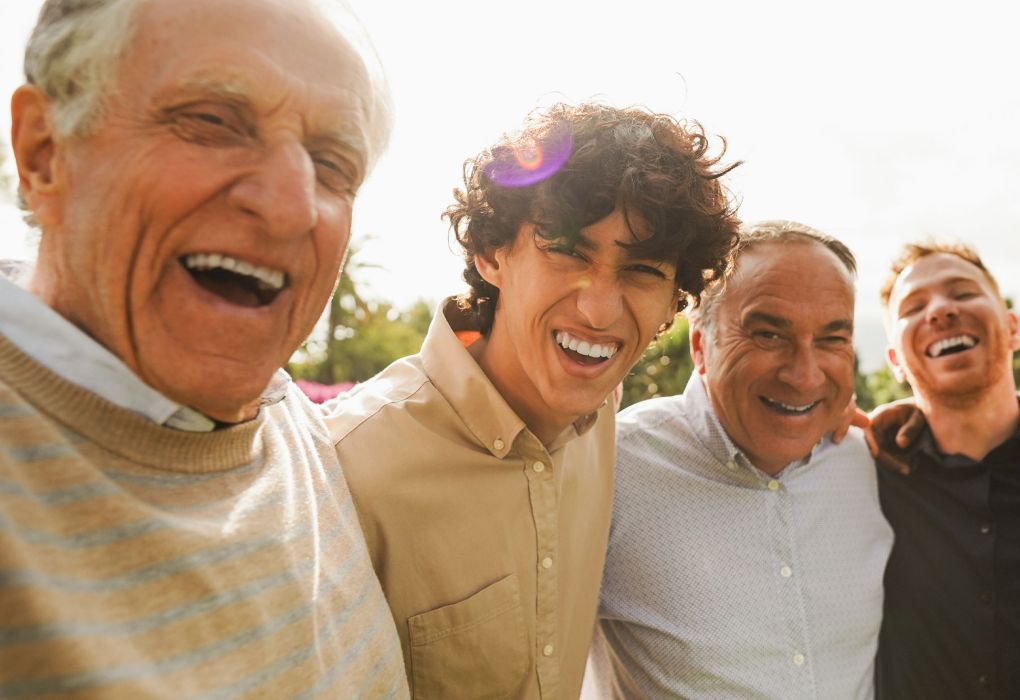 Vier Männer unterschiedlichen Alters lachen fröhlich in die Kamera