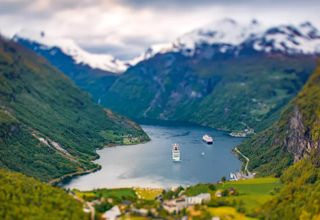 Aussicht auf grüne Berge und tiefblauen Fjord mit Booten im Wasser
