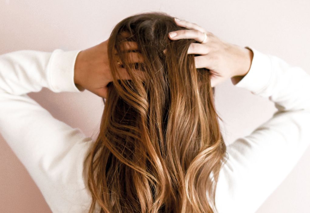 Frau fasst sich mit beiden Händen in ihre langen, gepflegten Haare