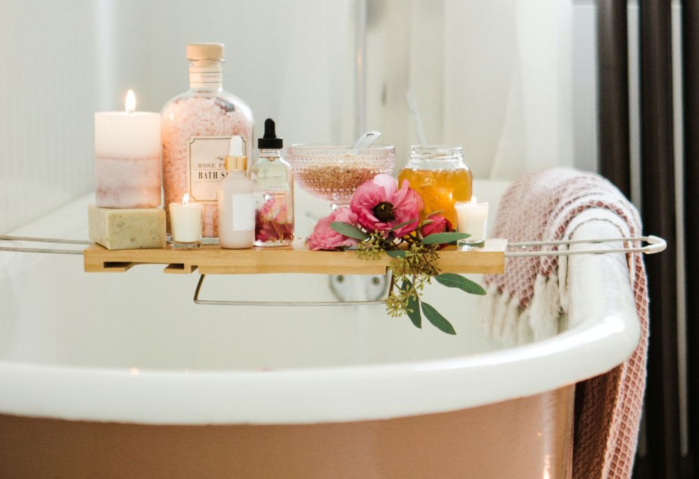 Badewanne mit Kerzen, Duftöl und Blüten