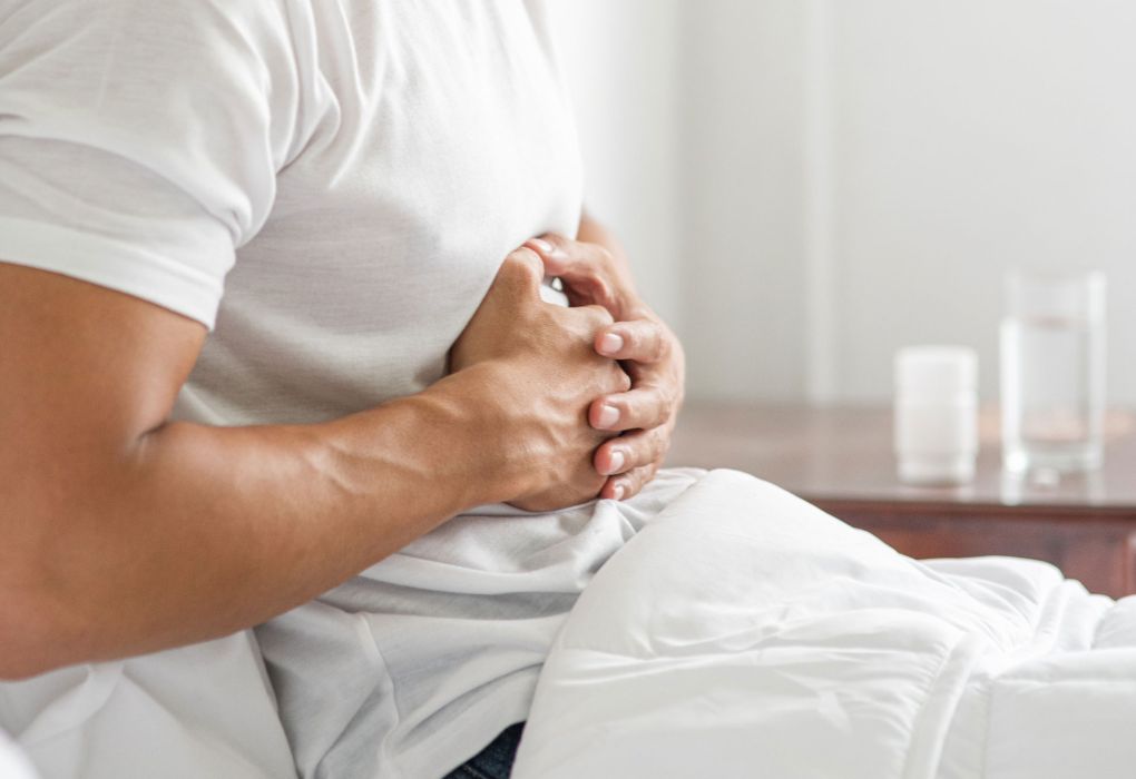 Mann hält sich sitzend mit beiden Händen den Oberbauch als Symbol für Sodbrennen