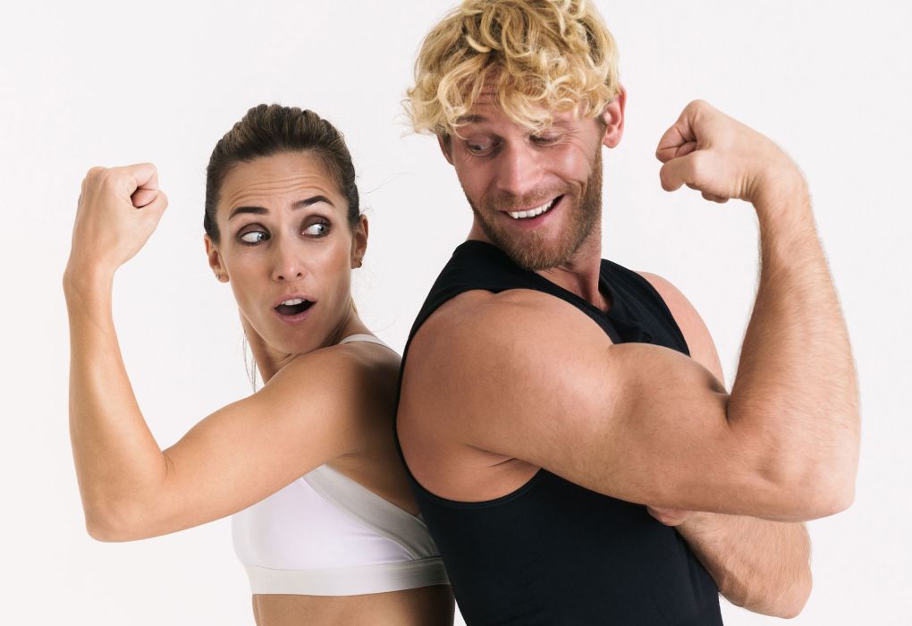 Zwei Personen stehen Rücken an Rücken und spannen ihre Oberarme an.