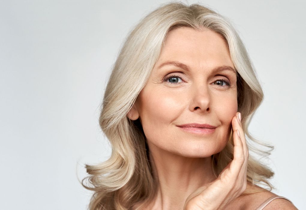 Reife Frau mit heller Haut lächelt, Symbol für Hautgesundheit.