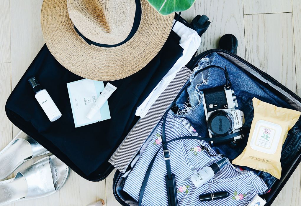 Offener Koffer mit Kleidung, Kamera und Reisezubehör.