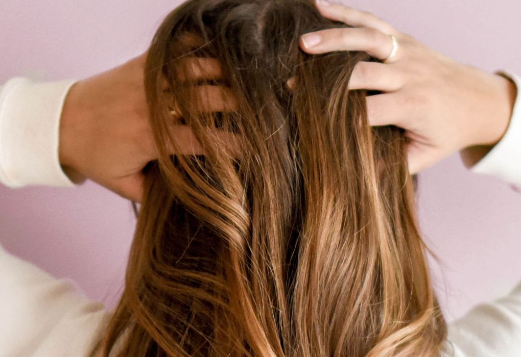 Frau von hinten fotografiert, hält ihre langen Haare in den Händen