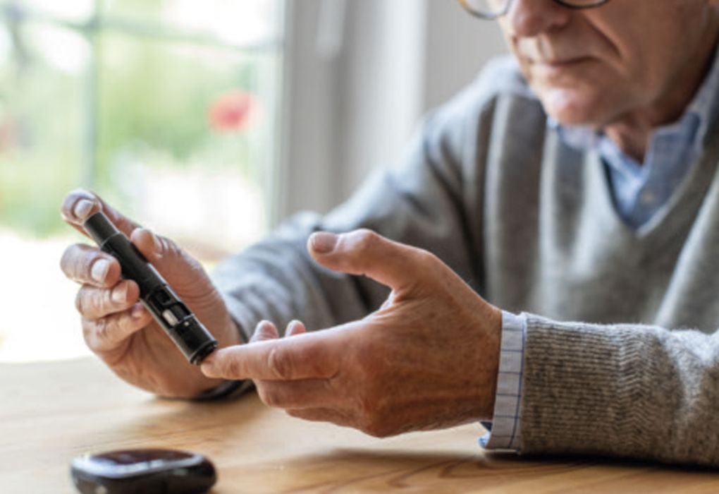 Mann misst seinen Blutzucker am Tisch