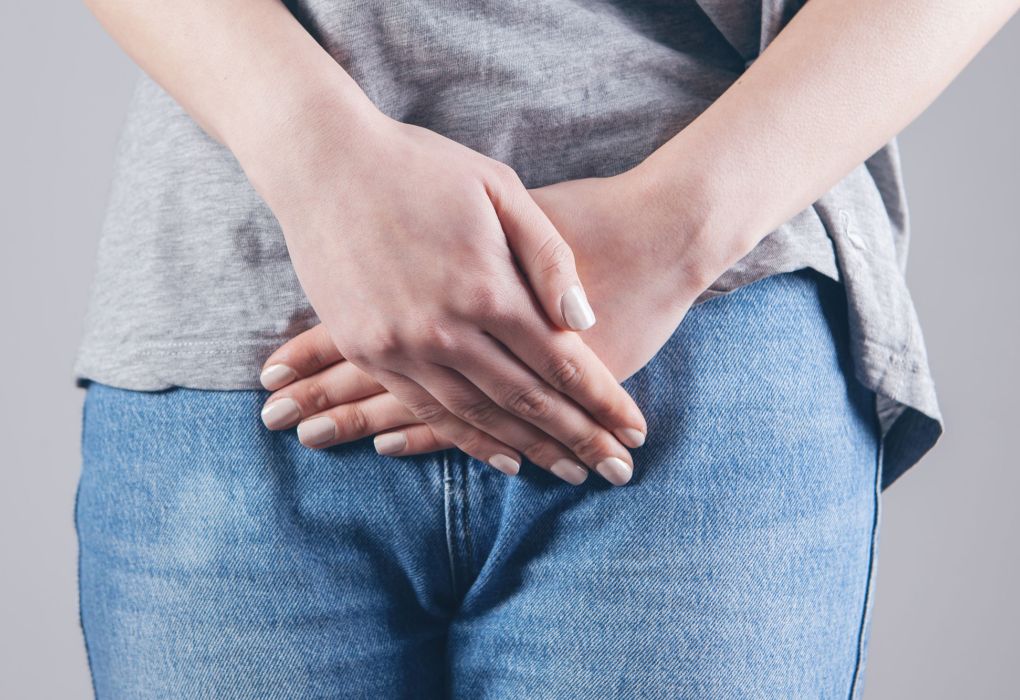 Frau hält sich mit beiden Händen den Bauch als Symbol für Regelschmerzen