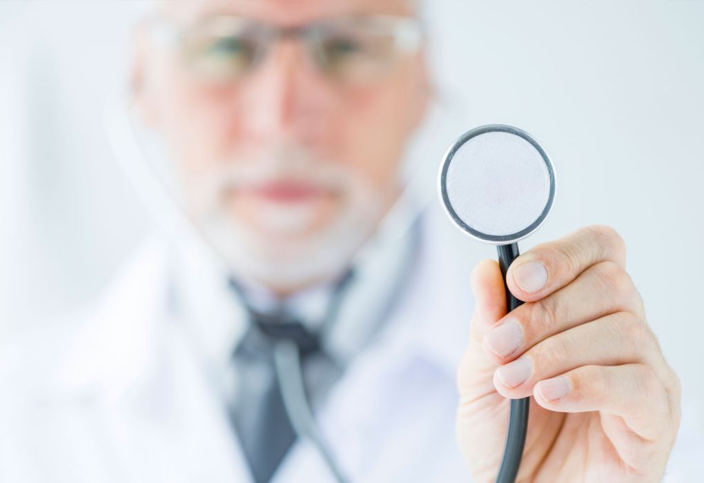Unscharfer Arzt im Hintergrund hält eine Lupe