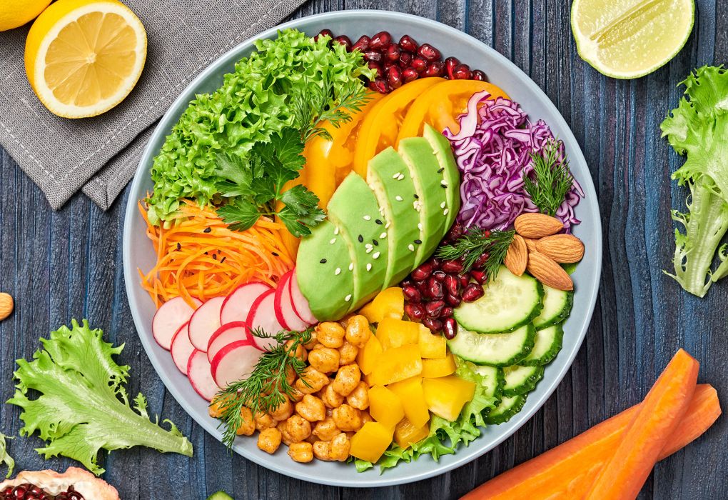 Schale mit verschiedenem Gemüse, Kirchenerbsen und Avocado von oben fotografiert.