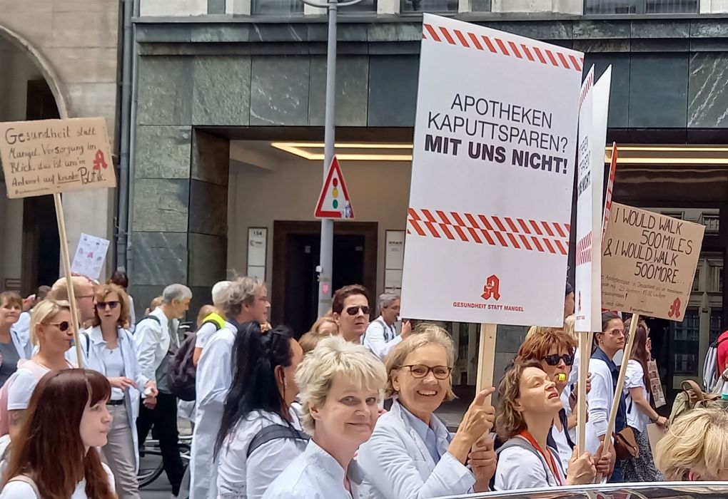 Menschen demonstrieren mit Schildern, Fokus auf Apothekenprotest.