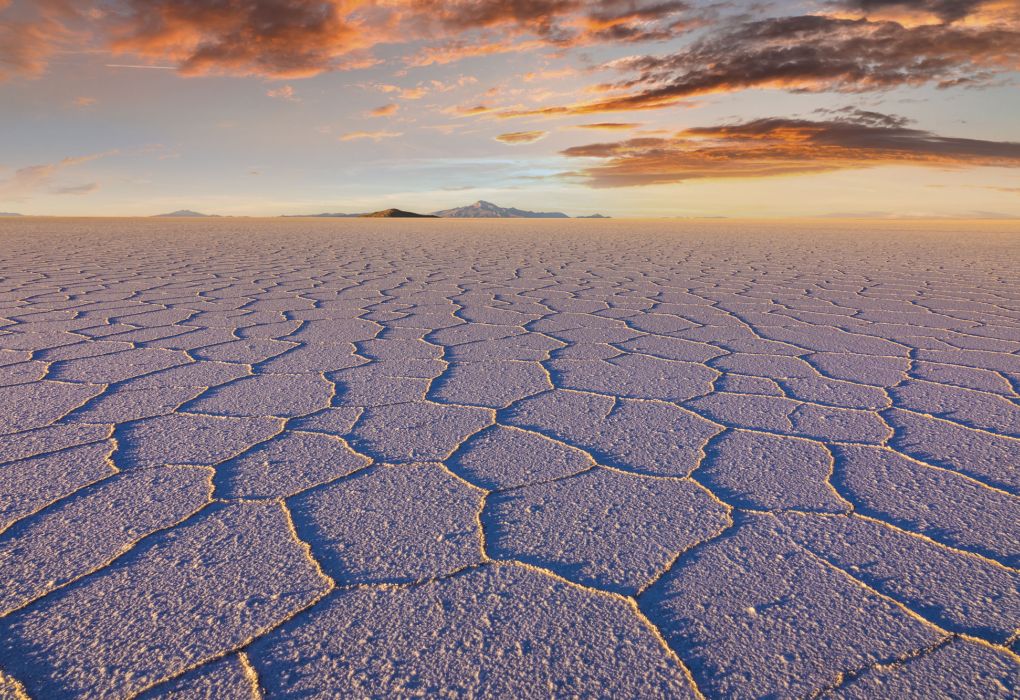 Ausgetrocknete Salzkruste mit polygonalen Mustern in einer weiten Wüstenlandschaft bei Sonnenuntergang