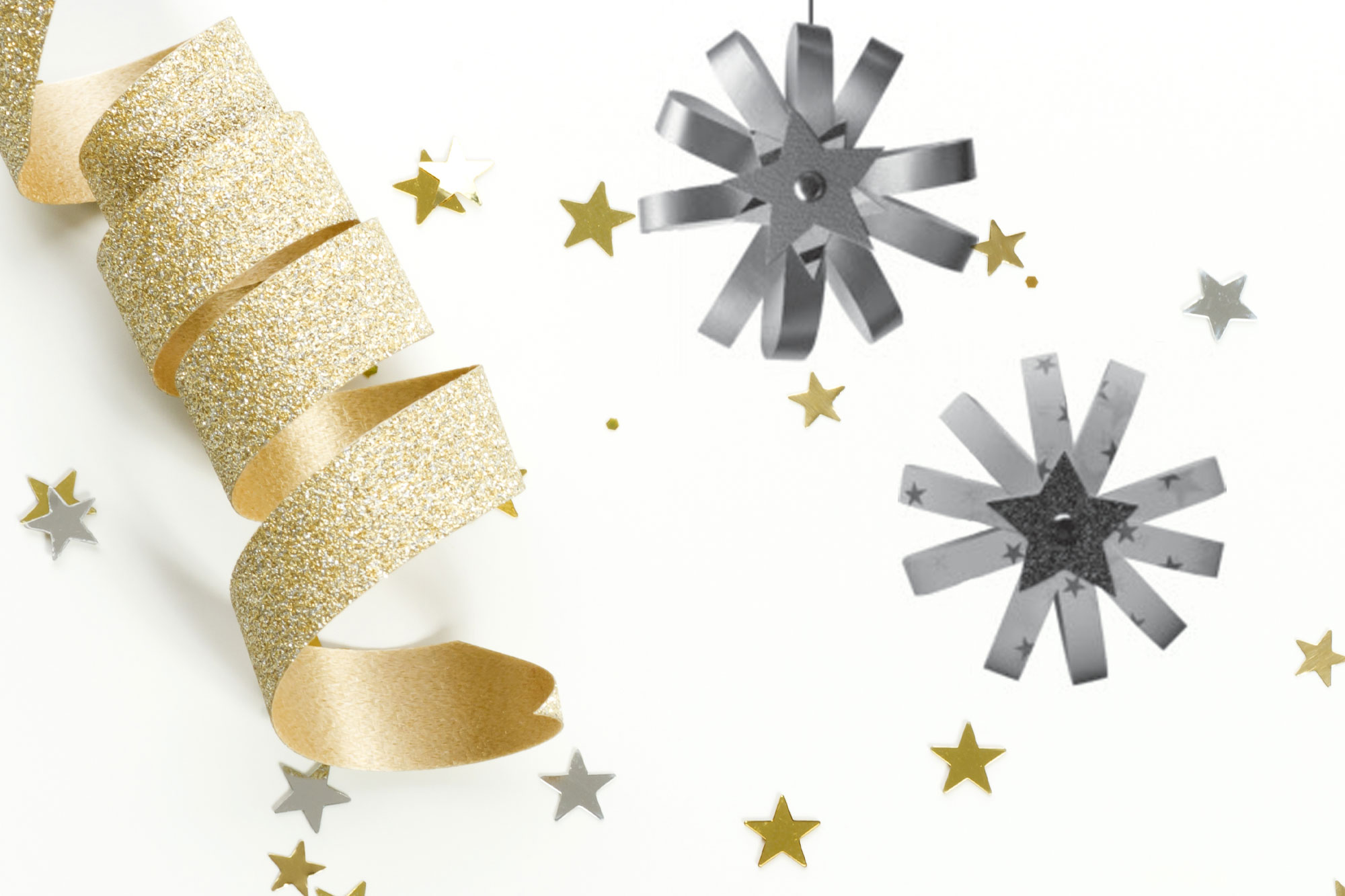 Goldene Geschenkbänder und silberne Papiersterne auf weißem Untergrund