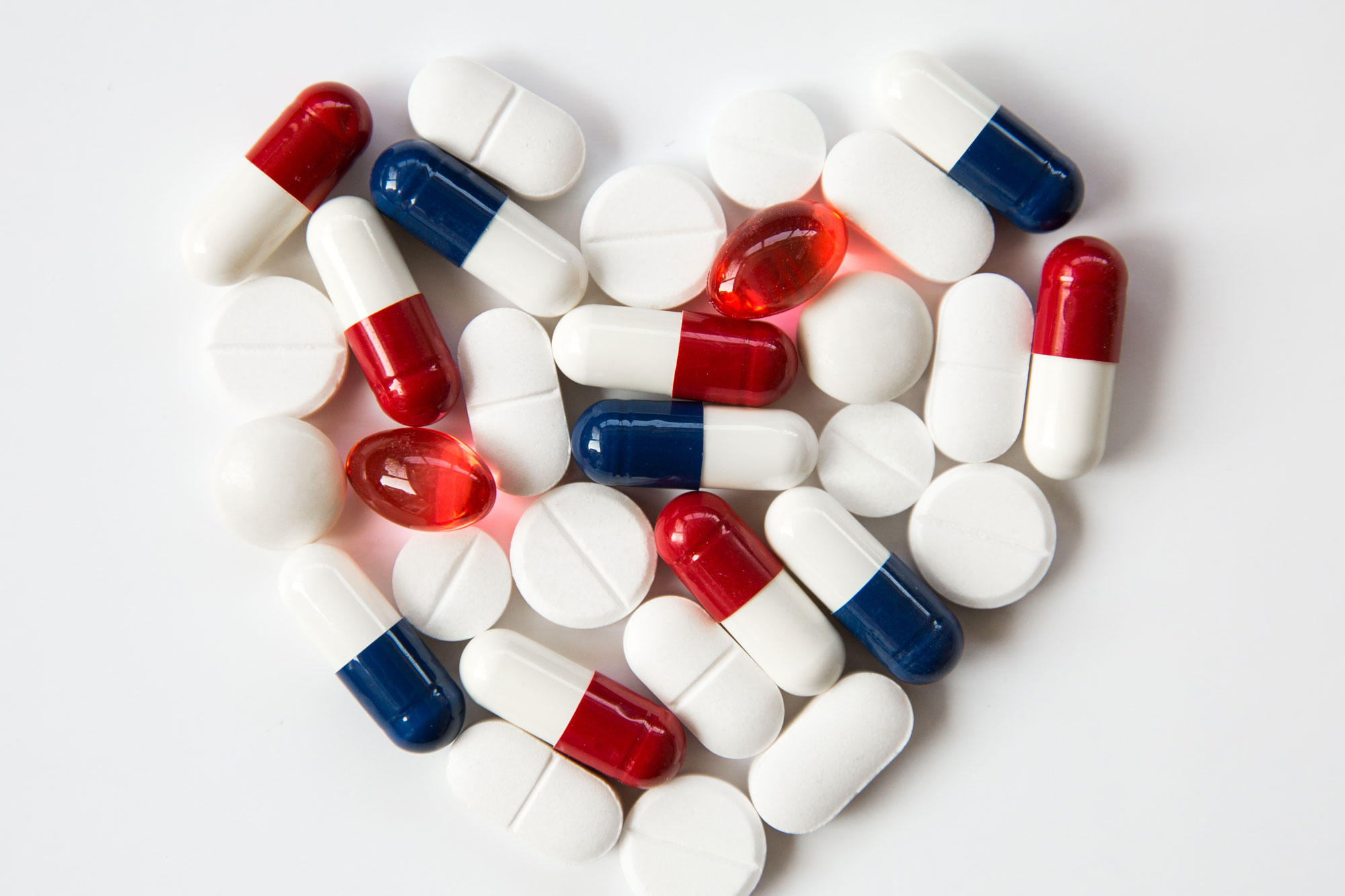 Rote, blaue und weiße Kapseln zu einem Herz auf weißem Hintergrund geformt