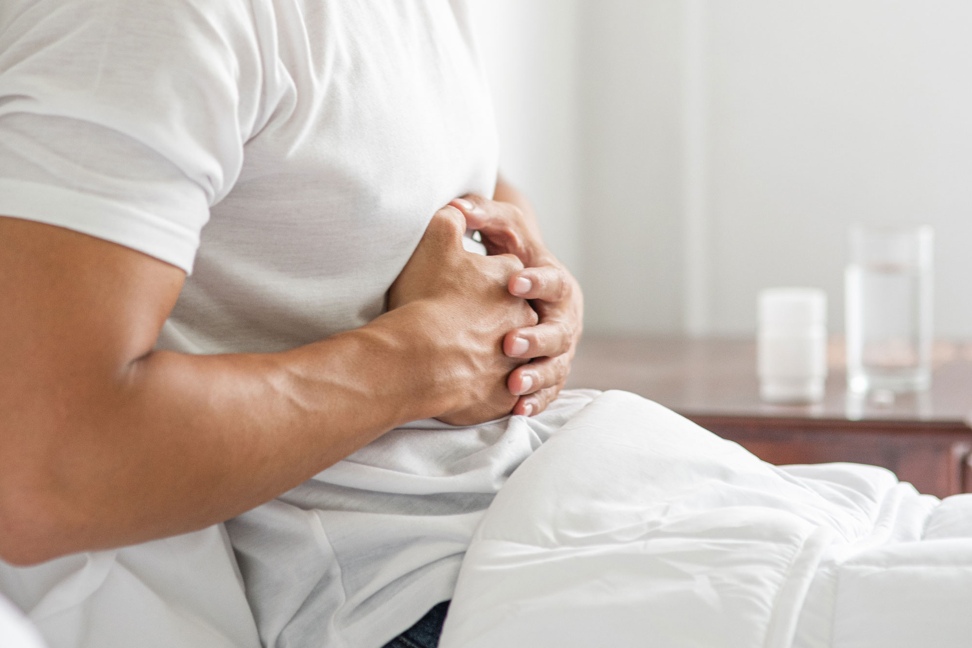 Mann hält sich sitzend mit beiden Händen den Oberbauch als Symbol für Sodbrennen