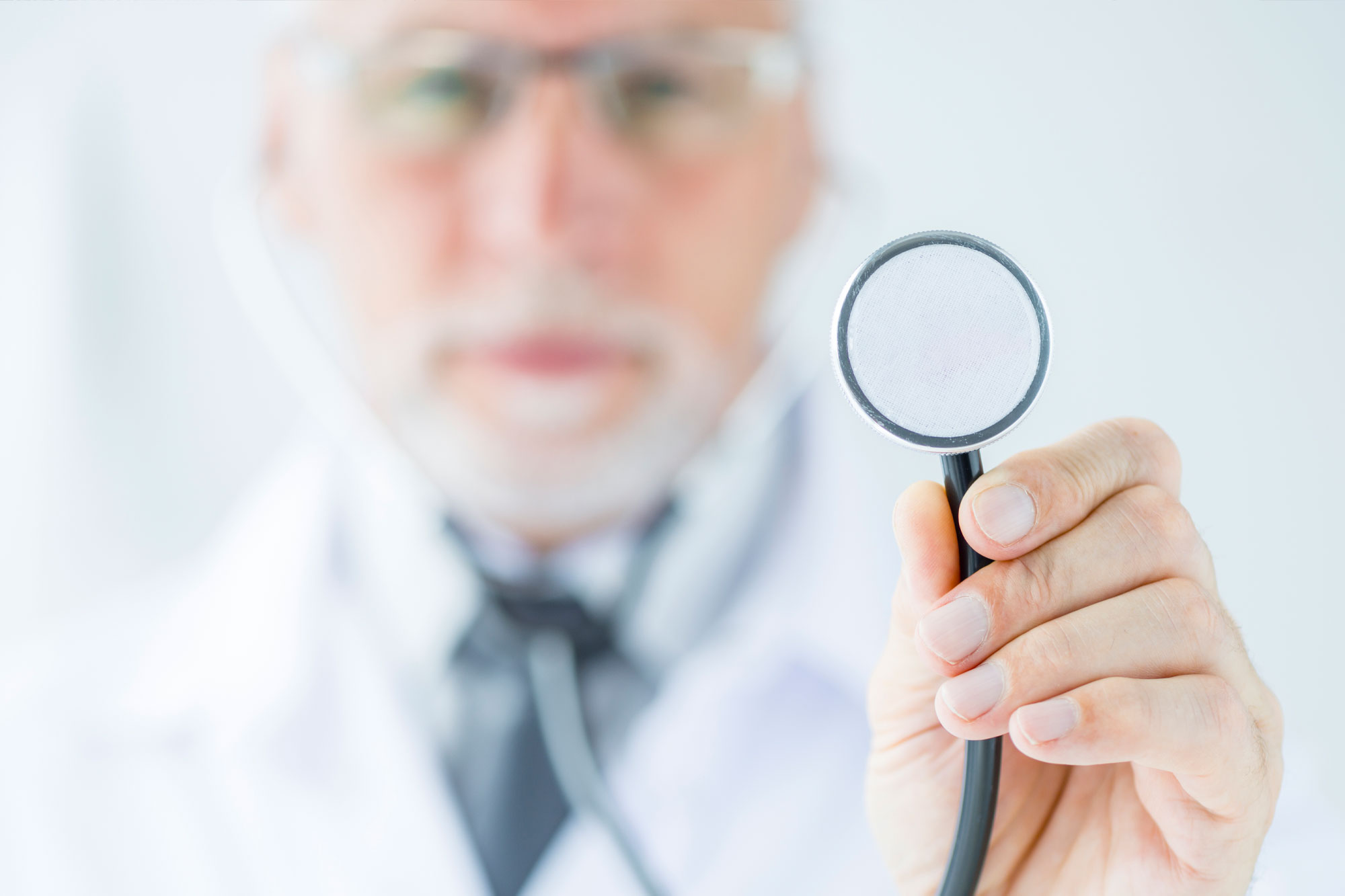 Unscharfer Arzt im Hintergrund hält eine Lupe