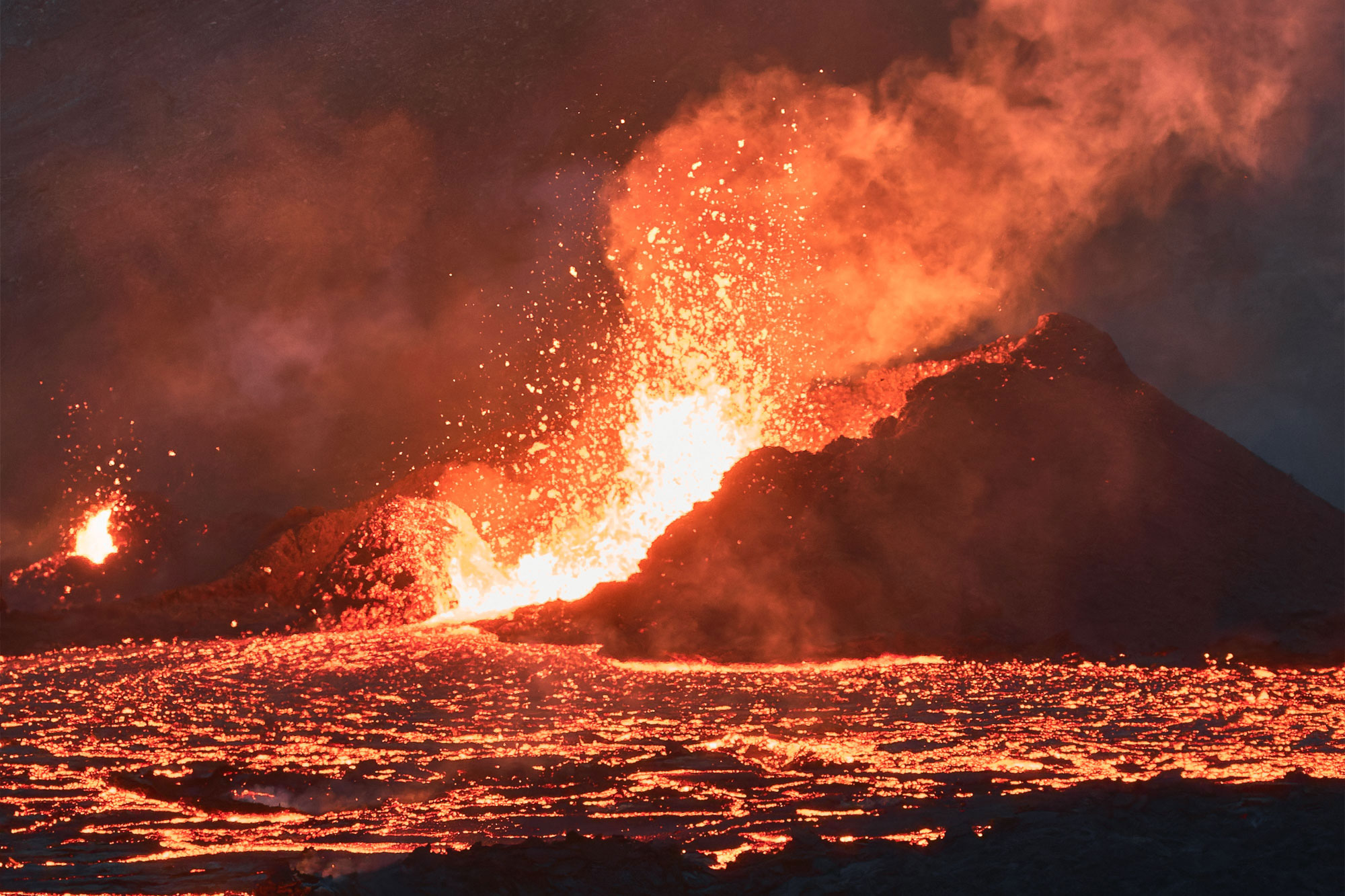 Aktiver Vulkan stößt Feuer, Rauch und Lava aus in der Nachtlandschaft