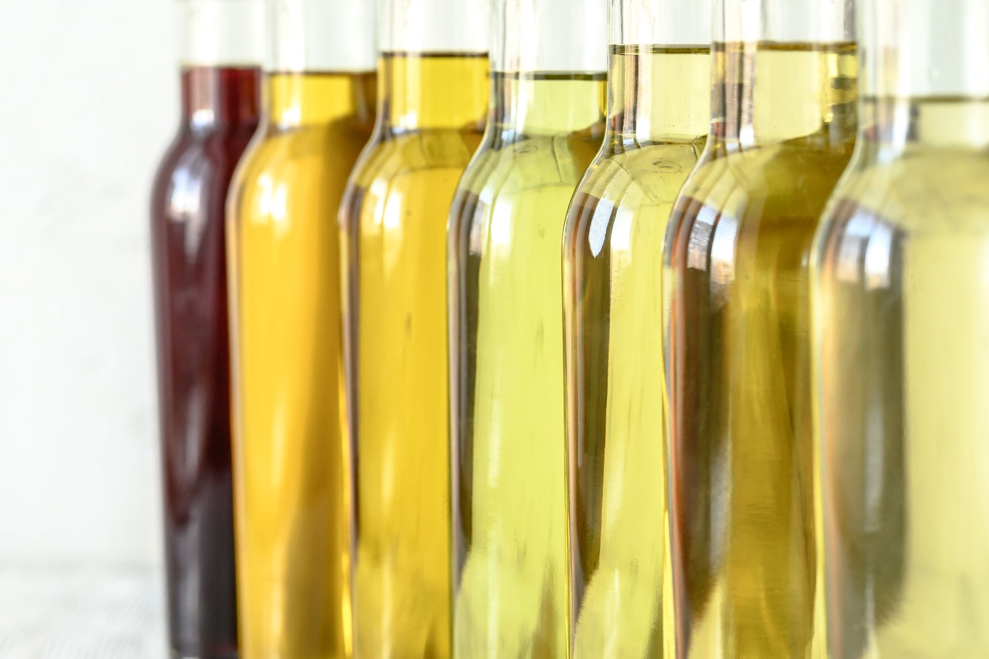 Mehrere Glasflaschen mit goldgelbem Öl in einer Reihe