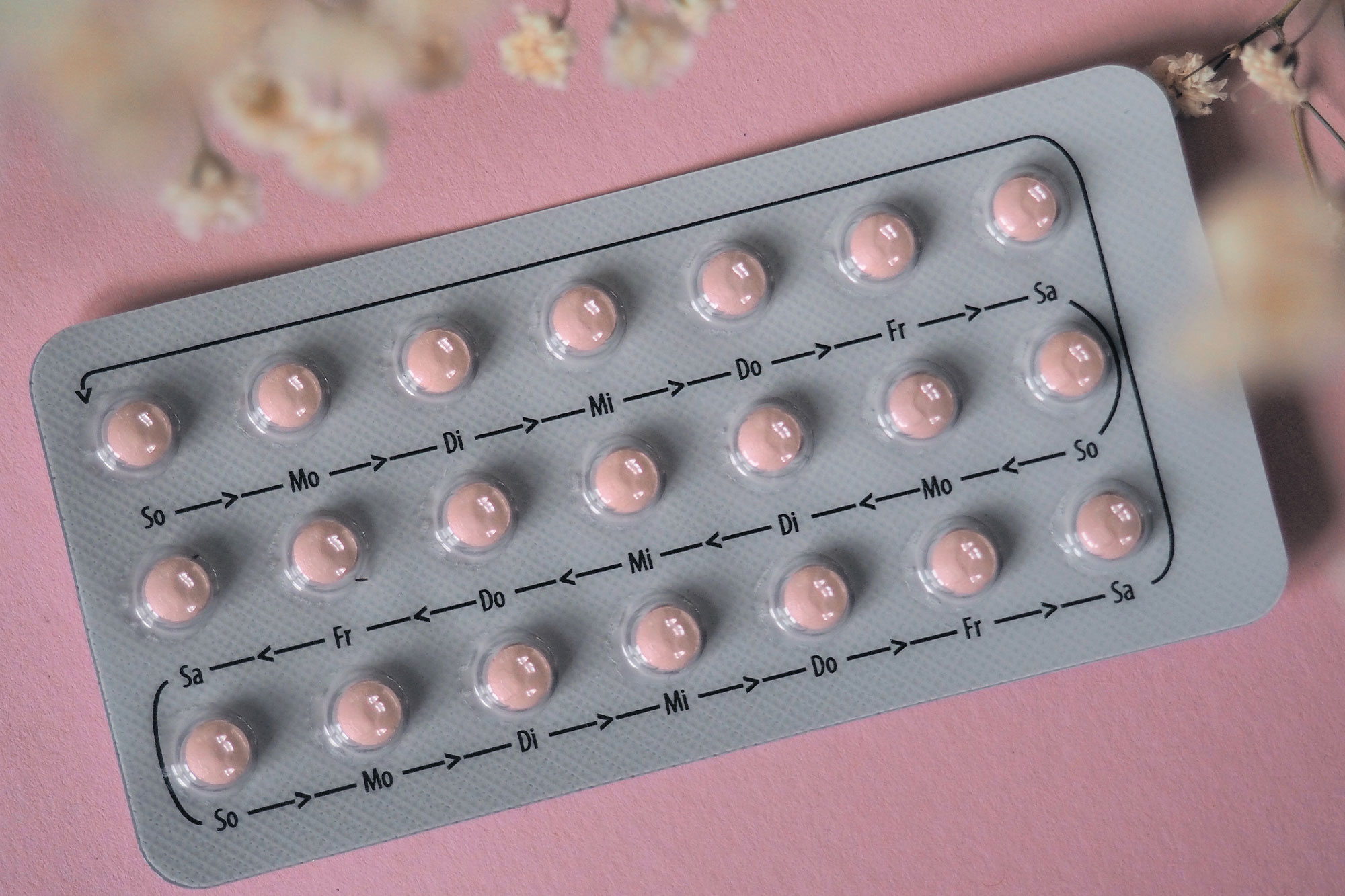 Silberne Blisterpackung mit rosa Tabletten vor rosa Hintergrund