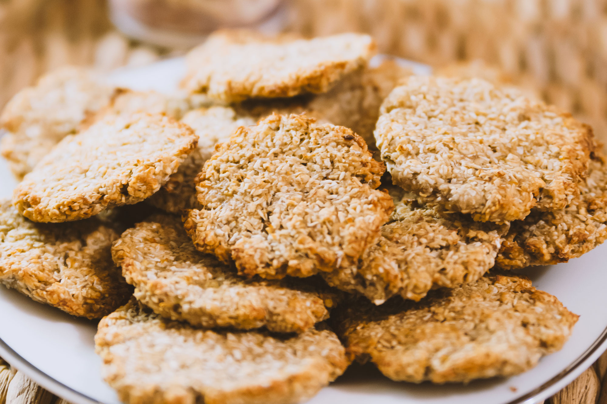 Teller mit goldbraunen Cookies aus Hafer und Körnern, angerichtet auf weißem Tell
