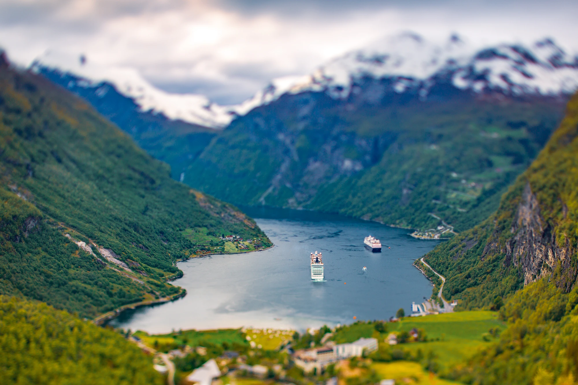 Aussicht auf grüne Berge und tiefblauen Fjord mit Booten im Wasser