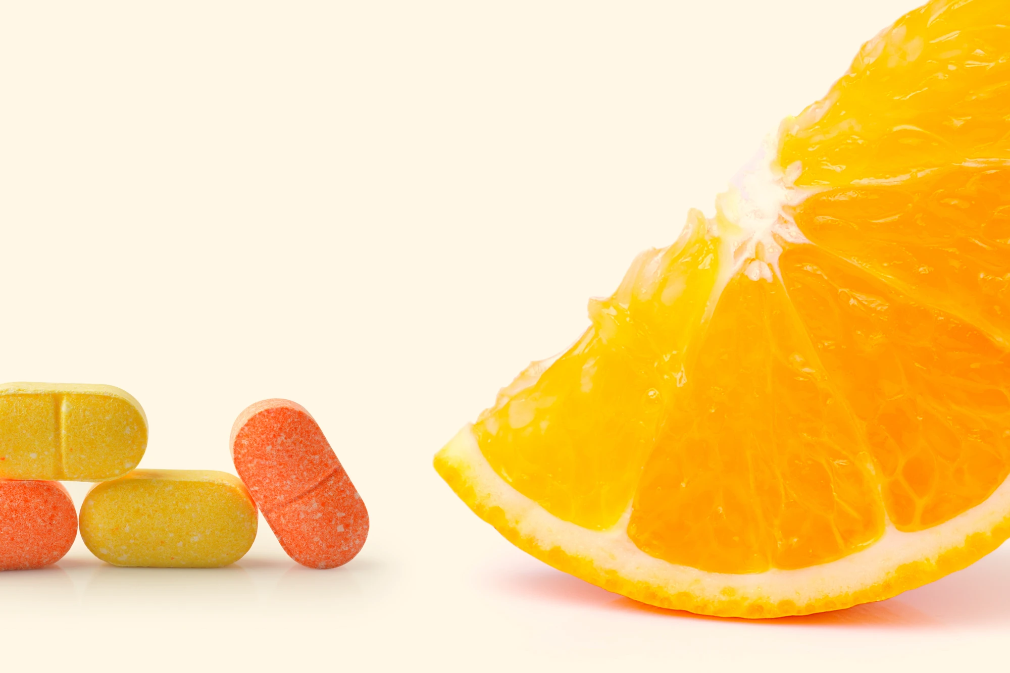 Aufgeschnittene Orange neben bunten Vitamin-Kapseln auf hellem Hintergrund