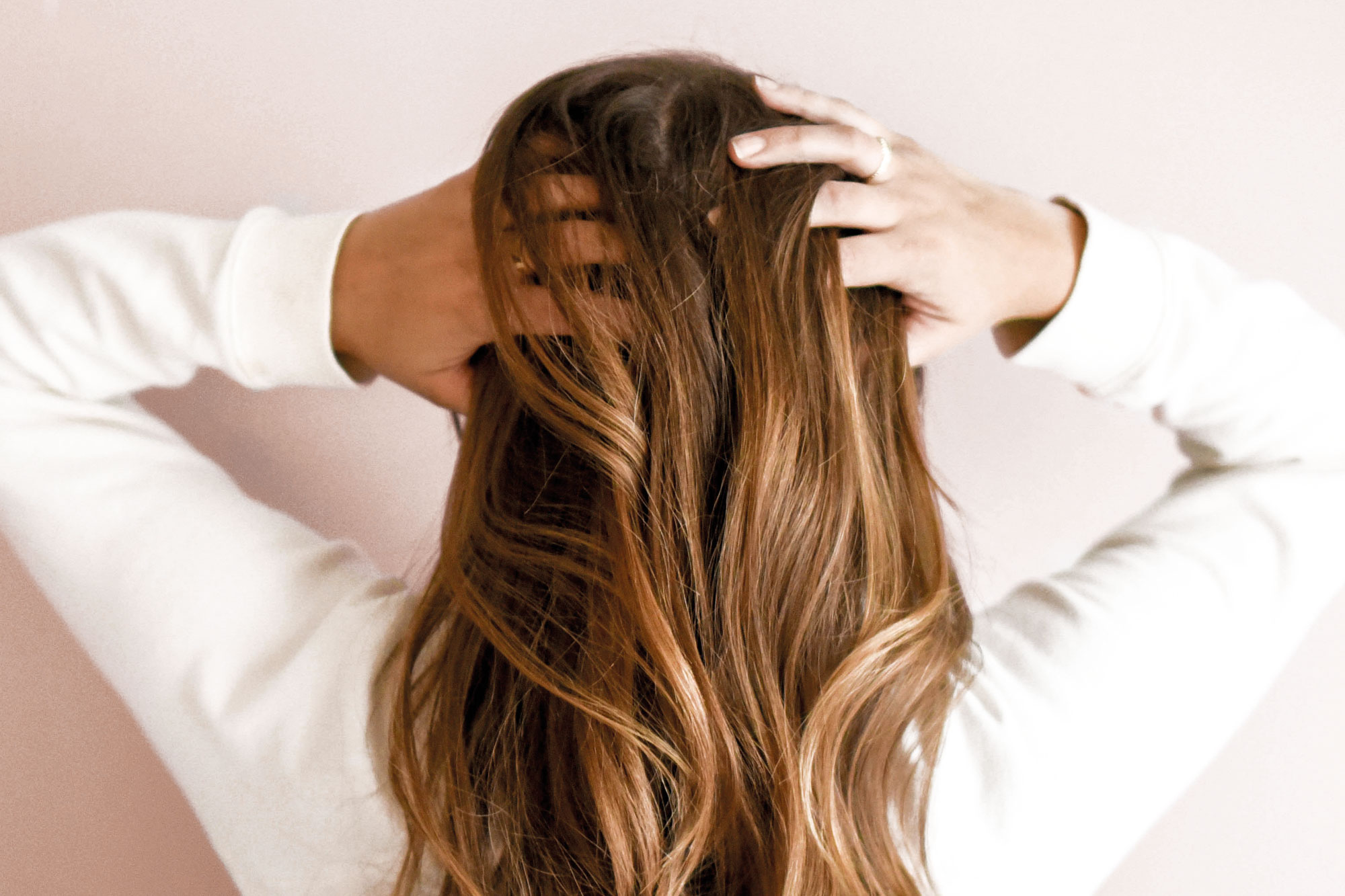 Frau fasst sich mit beiden Händen in ihre langen, gepflegten Haare