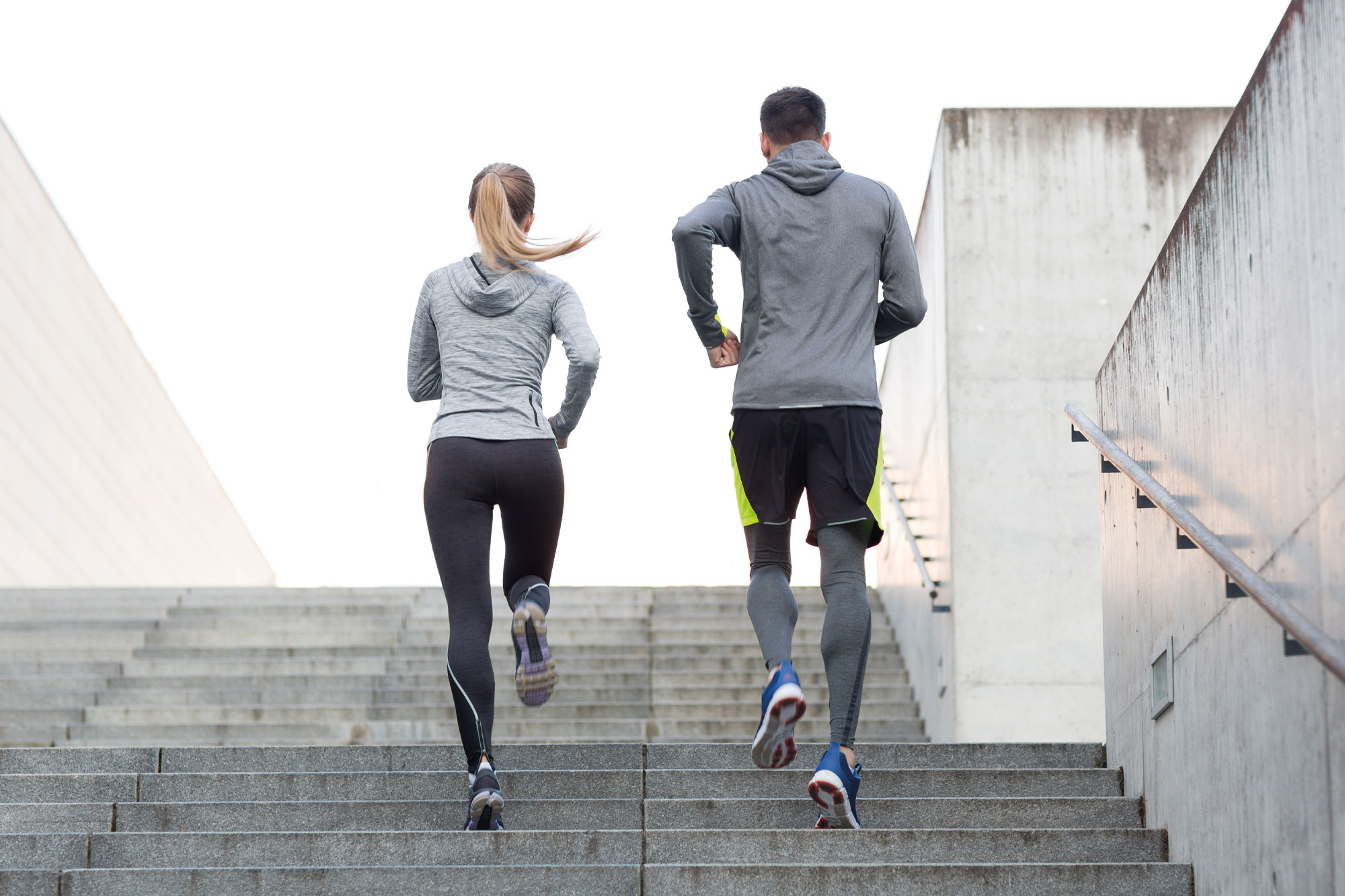 Zwei Personen in Sportkleidung laufen eine Treppe hoch als Trainingseinheit