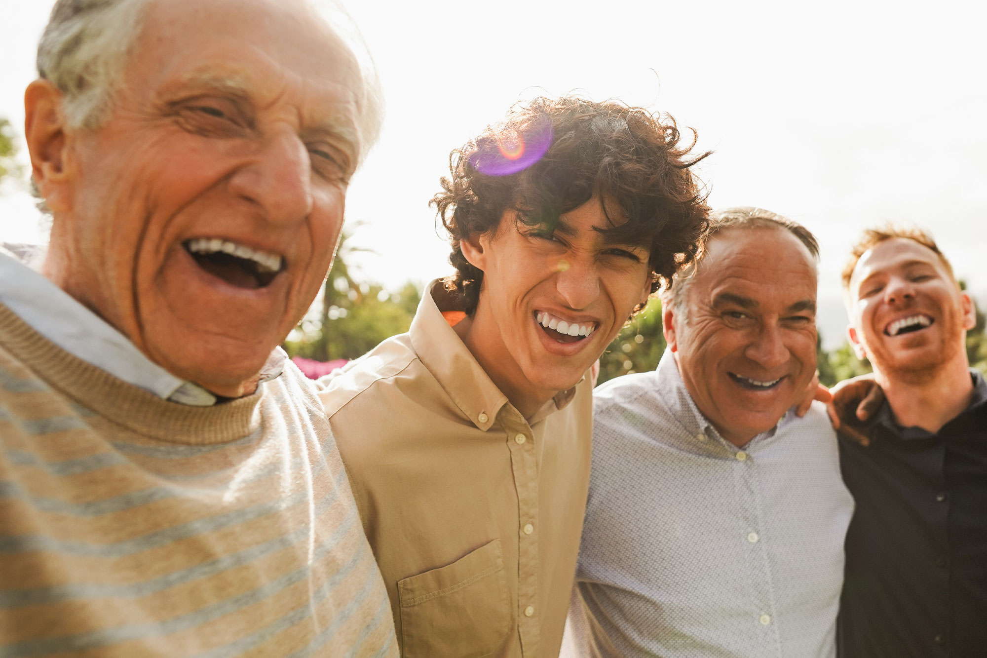 Vier Männer unterschiedlichen Alters lachen fröhlich in die Kamera