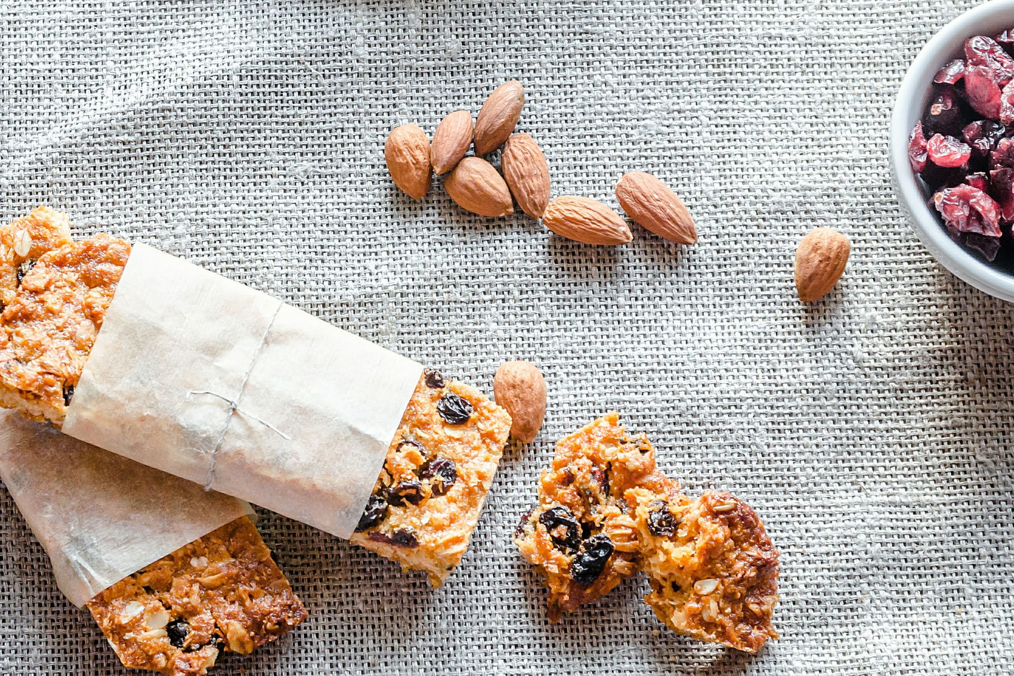 Verschiedene Müsliriegel mit Nüssen und Haferflocken auf grauer Unterlage