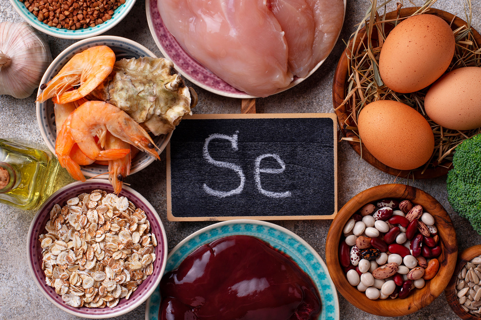 Lebensmittel wie Eier, Nüsse, Fisch und Getreide rund um eine kleine Tafel mit der Aufschrift „Se“