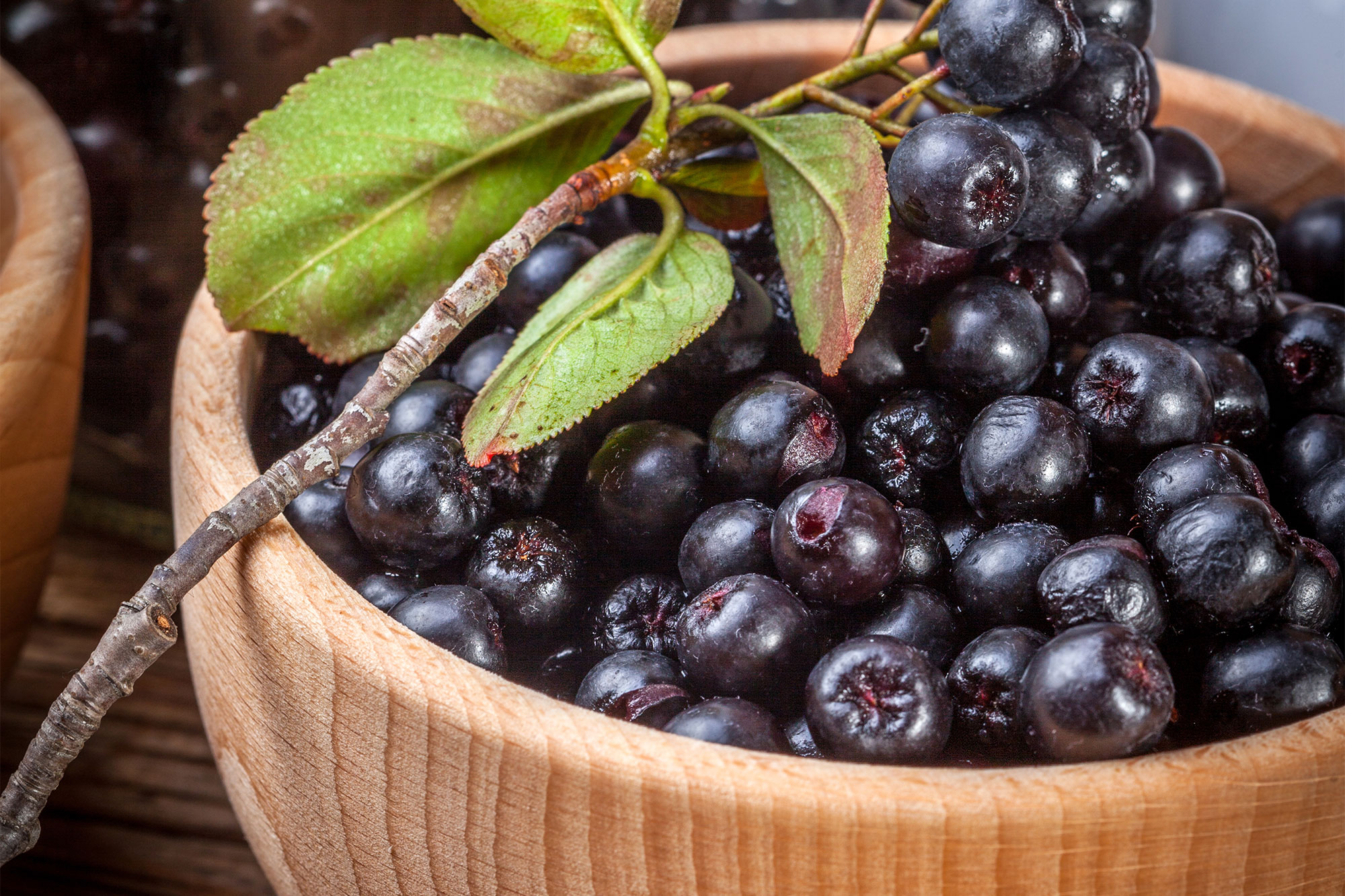 Frische schwarze Aroniabeeren in einer Holzschale