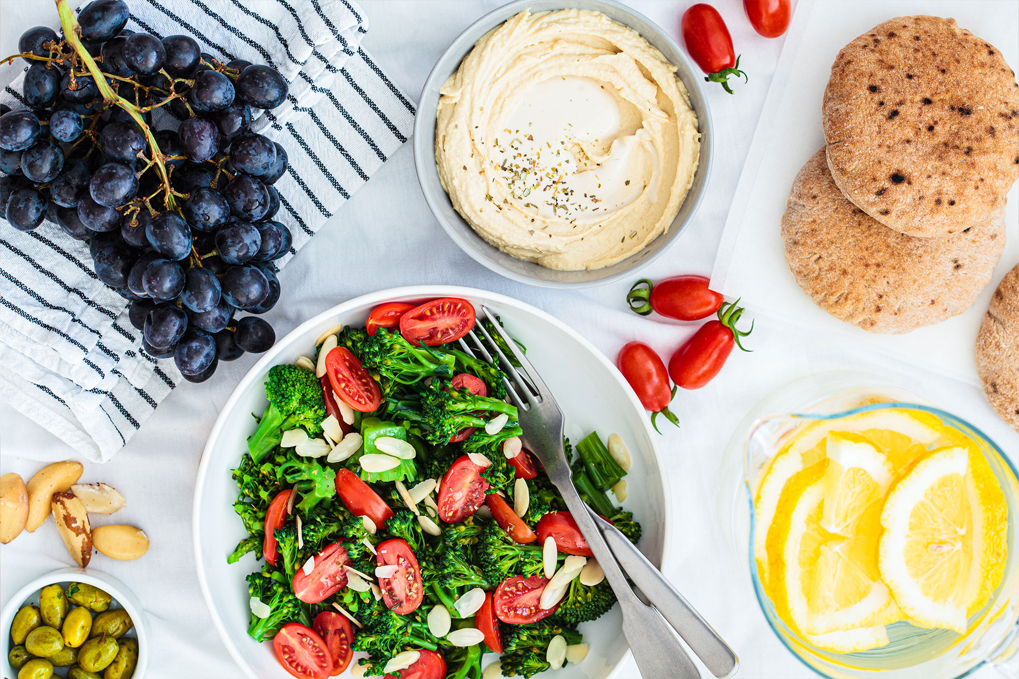 Oliven, Gemüse, Brot und Dip in Schalen, von oben fotografiert.